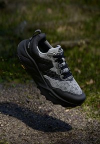 Baskets de course noires et grises avec tige en mesh, semelle en caoutchouc et design texturé. Comprend une languette de traction, des lacets et une marque "Fresh Foam".