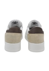 Sneaker bianchi con accenti in suede beige e marrone, con retro arrotondato, superficie liscia e suola in gomma bianca, che mostrano un design semplice.