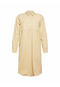 Robe chemise beige en tissu doux, dotée d'un col, de deux poches avant, de manches longues et d'un ourlet arrondi.