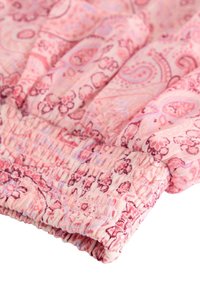 Tessuto a fantasia rosa con un polsino elasticizzato arricciato che presenta motivi floreali e paisley in un rosa più scuro e sottili accenti viola.