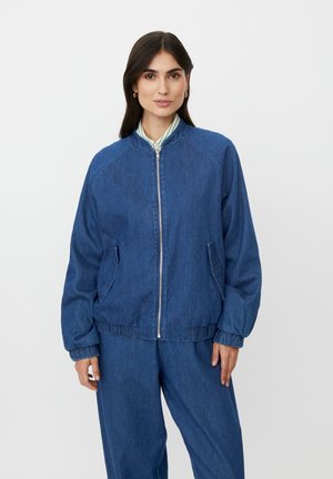 Kurtka dżinsowa w ciemnym niebieskim kolorze z zamkiem błyskawicznym z przodu, ściągaczami na rękawach i kieszeniami bocznymi. Charakteryzuje się klasycznym krojem bombera z dopasowaną talią.