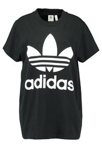 Svart bomullströja med en stor vit Adidas-logotyp och tre ränder nedanför. Kort ärm och rundhalsad design.