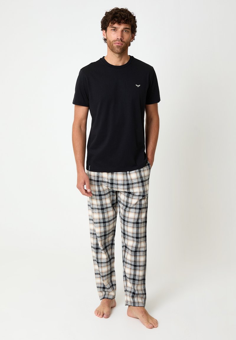 Black short-sleeve t-shirt with a small logo, paired with beige and black plaid flannel pajama pants, featuring an elastic waistband.