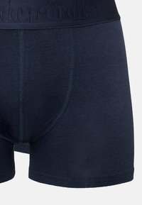 Marinblå bomullsboxer som har en strukturerad midjeresår med branding, platta sömmar och en tight passform, designad för komfort och stöd.