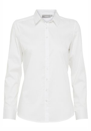 Chemise blanche à manches longues avec col pointu et taille cintrée, présentée sur un fond uni.