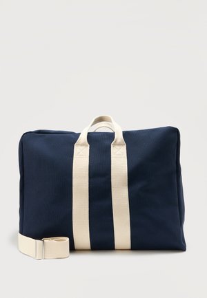 Geantă dreptunghiulară din material bleumarin, cu mânere duble bej și o curea de umăr bej reglabilă pe un fundal simplu.