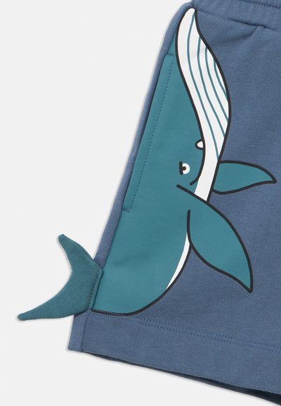 Μπλε βαμβακερά σορτς με γραφικό φάλαινας σε τιρκουάζ χρώμα με λευκές ρίγες και προεξέχουσα λεπτομέρεια ουράς σε τιρκουάζ. Ομαλή υφή με ραμμένα άκρα.
