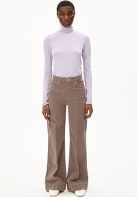 Bruine ribfluwelen wijde broek en een lichtpaarse lange mouw turtleneck top, met een aansluitende pasvorm en een zachte stoffen textuur.