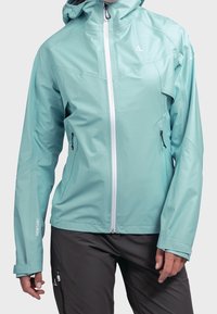 Veste imperméable bleu clair avec capuche, fermeture éclair frontale et deux poches latérales. Présente un design élégant et des poignets ajustables.