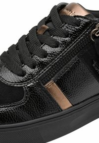 Baskets noires avec une tige brillante et texturée, dotées de lacets noirs, d'une bande d'accent dorée et d'une semelle en caoutchouc noir. Détail de fermeture éclair sur le côté.