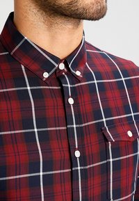 Rode en marineblauwe geruite shirt met een button-down kraag, witte knopen, een enkele zak op de borst en een gestructureerde pasvorm. Gemaakt van katoen.