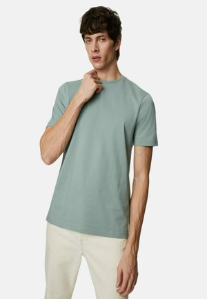 Lichtgroene katoenen t-shirt met korte mouwen, ronde halslijn en een fijne textuur. Ggedragen door een model met een neutrale uitdrukking.