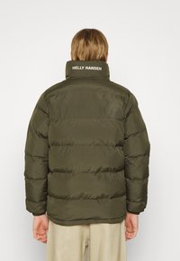 Alkoholio žalia pūkinė striukė su aukštu apykakle, siuvinėtu dizainu ir išsiuvinėtu "HELly HANSEN" logotipu ant nugaros. Minkšta, lygi tekstūra.