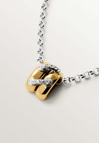 Collar de oro y plata que presenta un cierre grueso y pulido con acentos de piedras preciosas transparentes sobre una cadena de plata eslabonada.