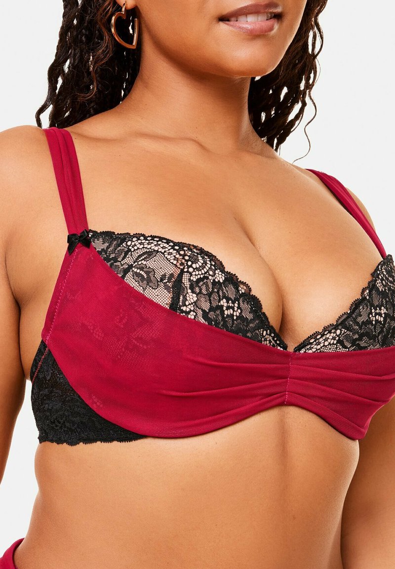 Soutien-gorge bordeaux et noir avec des bonnets en dentelle, un tissu lisse, des bretelles réglables, et un design torsadé au centre avec un accent en nœud.