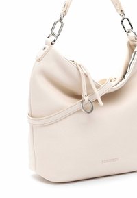Sac à main en cuir beige clair avec un design flasque, accents en fer blanc et fermeture à cordon. Présente un logo de marque en relief.