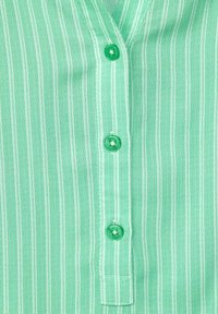Camicia a righe verdi con tessuto strutturato, scollatura a V e bottoni verdi al centro, con sottili righe bianche alternate.