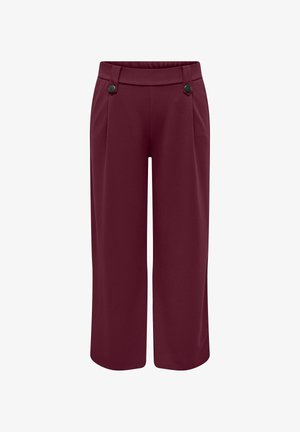 Bordowe spodnie o szerokich nogawkach z gładką teksturą, z płaskim paskiem, dwoma plisami z przodu oraz dwoma zielonymi guzikami jako ozdobą.