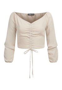 Top cropped beige chiaro con scollatura a barchetta, dettagli arricciati nella parte anteriore e maniche a sbuffo elasticizzate. Include un laccio regolabile all'orlo.