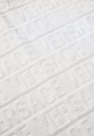 Biely textil s vyrazeným opakujúcim sa textovým motívom. Textúra je hladká s jemným leskom, ktorý zvýrazňuje dizajn písma.