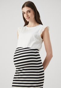 Mammakjole med hvit topp med blonder på ermene og sorte-hvite striper i skjørtet, designet for komfort og stil.