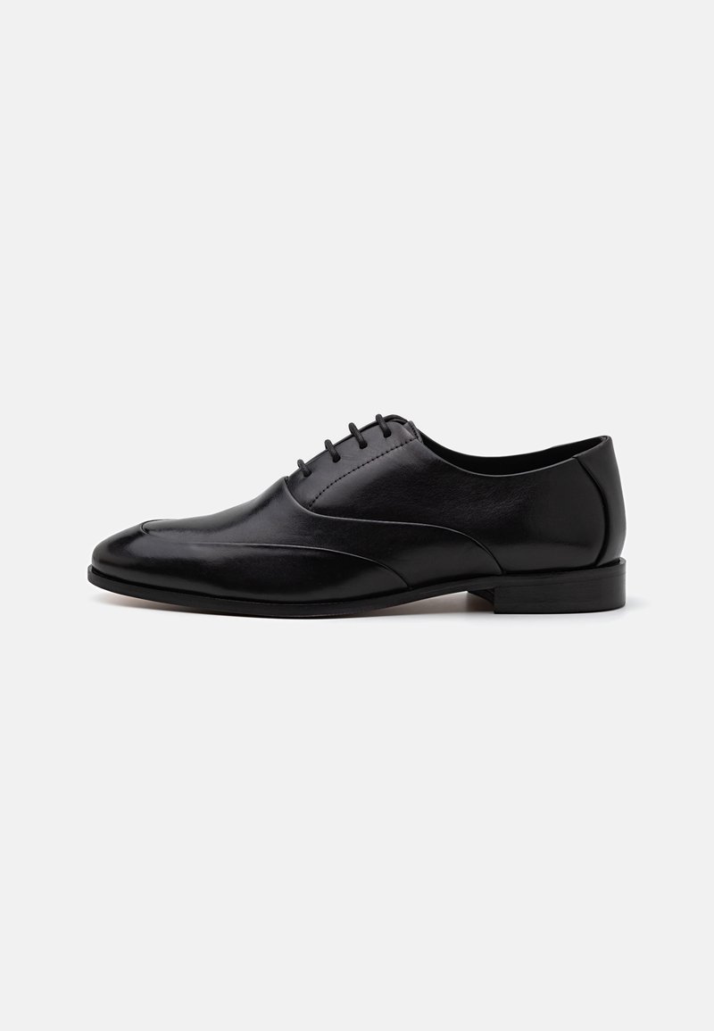 Pantofii din piele neagră cu vârful ascuțit, design elegant și toc mic. Au cinci găuri pentru șireturi și detalii subtile de cusătură pe partea superioară.