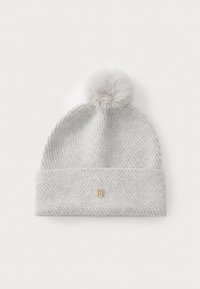 Lichtgrijze gebreide beanie met een omgeslagen boord, voorzien van een decoratieve pompon bovenaan en een klein gouden logo aan de voorkant.