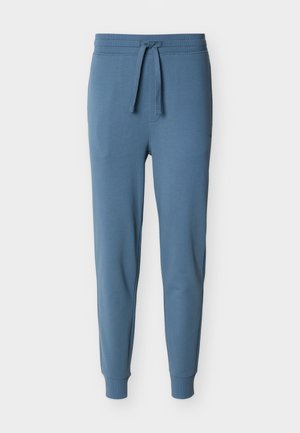 Pantalon de jogging slim bleu avec taille côtelée, cordon de serrage et poignets côtelés sur fond blanc.