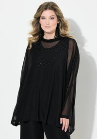 Tunica nera in chiffon con collo rotondo e decorazioni in cristallo, silhouette fluida e maniche lunghe e trasparenti. Tessuto morbido.