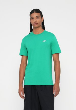 T-shirt en coton vert à manches courtes et col rond. Présente un petit logo Nike blanc sur la poitrine gauche. Texture lisse.