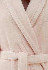 Accappatoio rosa chiaro realizzato in morbido tessuto testurizzato. Caratterizzato da un collo a scialle, apertura incrociata e una cintura coordinata in vita.