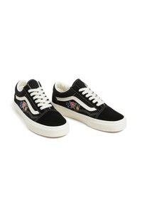 Schwarze niedrige Sneaker mit weißen Schnürsenkeln und Sohlen, die florale Stickereien und einen weißen Seitenstreifen auf weißem Hintergrund aufweisen.