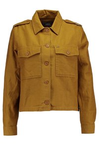 En kortad, senapsgul jacka i bomull med knäppning framtill, två bröstfickor och en krage med axelklaffar på axlarna.