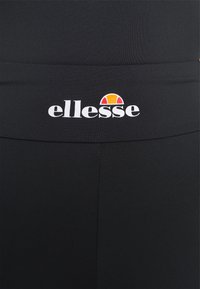 Tissu noir avec logo ellesse blanc et détail en demi-cercle orange-rouge centré sur la ceinture du vêtement.