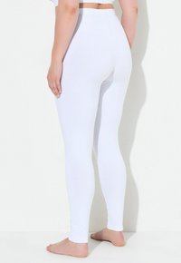 Bílé legíny z elastického materiálu, přiléhavý střih, elastický pás, celý délka, hladká textura, bez viditelných vzorů nebo kovových prvků.