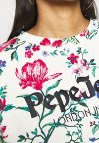Kwiatowy sweatshirt na białym tle, ozdobiony intensywnymi czerwonymi i niebieskimi kwiatami. Czarny haftowany napis "Pepe Jeans LONDON."