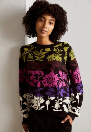 Knit sweater featuring a multicolor floral pattern in shades of green, pink, purple, and black. Ribbed neckline and cuffs, relaxed fit.