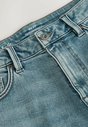 Šviesiai mėlynos spalvos džinsai, pagaminti iš džinso audinio, su tiesiu kirpimu, metaline sagtele užsegimui ir kontrastingais siūlais juosmens diržo ir šoninių siūlių srityje.