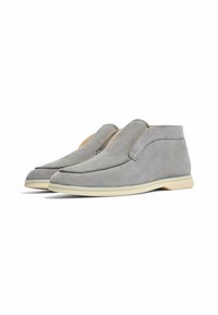 Zapatos de ante gris con un diseño simple, que presentan un estilo sin cordones, punta redonda y una suela de goma color crema.