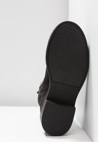 Botín de ante negro con suela de goma negra texturizada, cremallera lateral y acentos decorativos en plata. Talla marcada como 37.