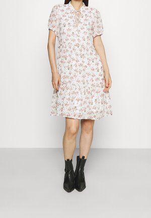 Blomstret kjole med korte pufærmer, hvid baggrund, pink og grønne blomster, knaplukning foran, kombineret med sorte ankelstøvler.