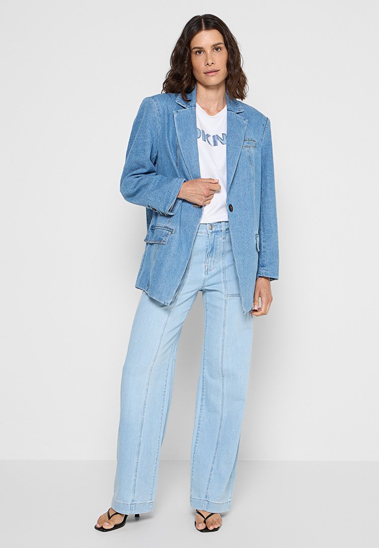 Blazer de mezclilla azul claro con corte relajado, cierre de un botón y bolsillos parche, combinado con pantalones de mezclilla de talle alto de lavado claro.