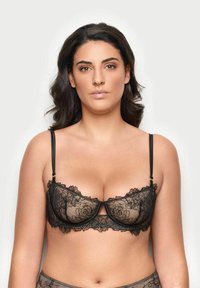 Černá krajková podprsenka s květinovým vzorem, průhlednými košíčky a nastavitelnými ramínky. Má vlnkový okraj a zapínání na háček a očko na zadní straně.