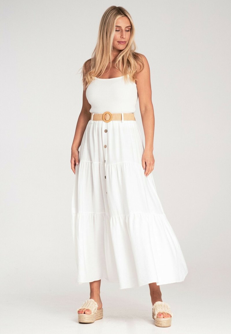 Biała długa sukienka z dopasowanym prążkowanym topem, warstwową spódnicą, guzikami z przodu i plecionym paskiem. Połączona z sandałami na platformie.