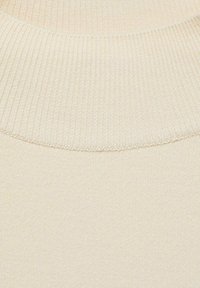 Light beige knit sweater fabric with a ribbed texture. The neckline features a wide, snug ribbed collar. No visible patterns or hardware.