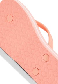 Neonově růžová guma na flip-flopy s texturovaným povrchem, který obsahuje kruhové gripové vzory a dvě kruhové otvory pro odvodnění nebo ventilaci.