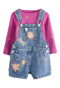 Overoles de mezclilla en azul, con apliques coloridos de estrellas y personajes, combinados con un top rosa de manga larga y textura acanalada. Diseño brillante y divertido.