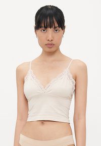 Beige top met kantafwerking op de halslijn, dunne verstelbare bandjes en een aansluitend ontwerp. Zachte stof met een gladde textuur.