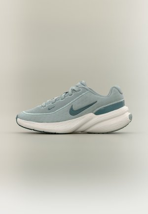 Světlle modrá běžecká bota Nike s horní částí z prodyšné síťoviny, polstrovanou bílou podrážkou a tmavě modrým logem Swoosh na neutrálním pozadí.