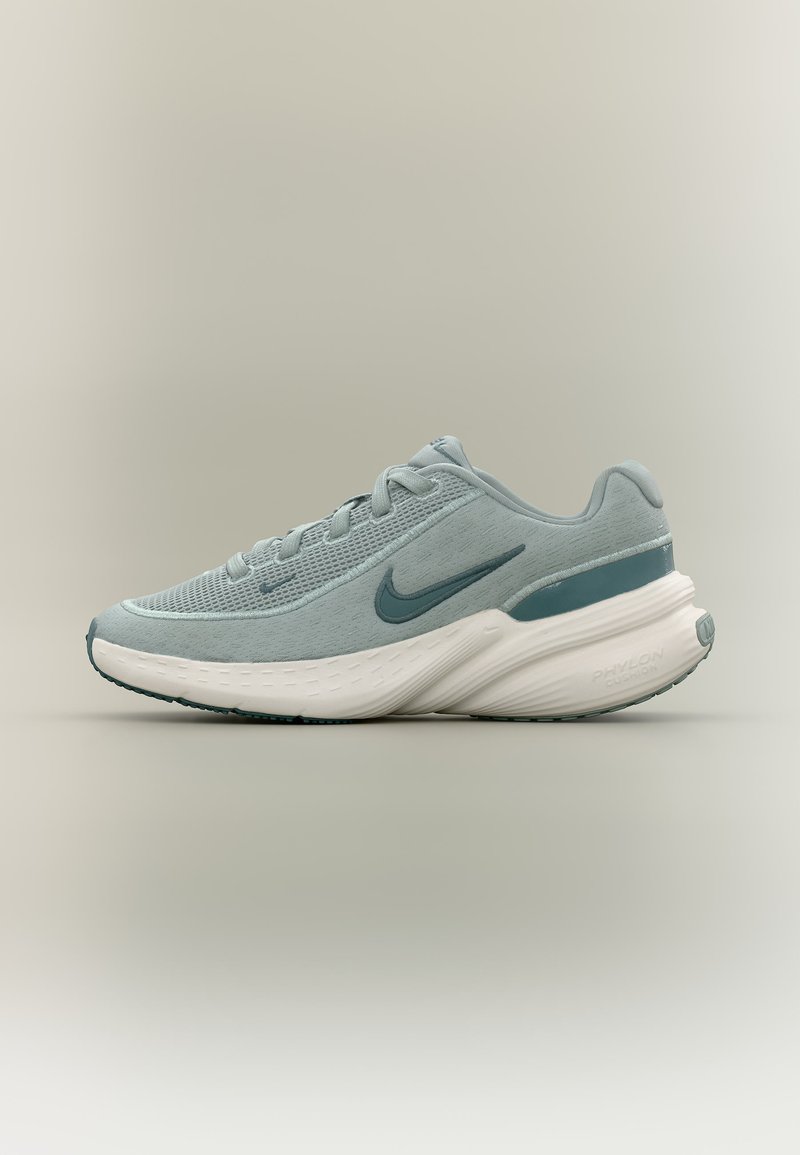 Ανοιχτό μπλε αθλητικό παπούτσι Nike με πλέγμα επάνω μέρος, μαλακή λευκή σόλα και σκούρο μπλε λογότυπο Swoosh σε ουδέτερο φόντο.